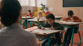 Back view unknown woman school tutor teacher asking multiracial multiethnic children four kids pupils in class lesson African American ethnic clever boy raising hand arm answering studying education - Powered by Shutterstock - Get 15% off with code: PIKWIZARD15