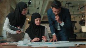 Arabian business team three partners drawing blueprint building plan in office together businessman muslim businesswomen in hijab teamwork architecture paperwork engineers architects designers work - Powered by Shutterstock - Get 15% off with code: PIKWIZARD15
