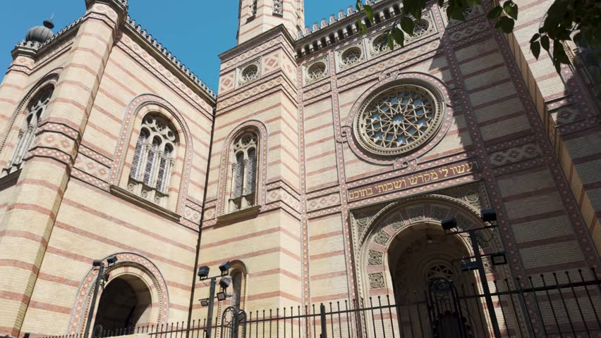 Panning across the exterior of the Dohány Street Synagogue in Budapest, showcasing its ornate facade, Moorish Revival architecture, and intricate decorative details