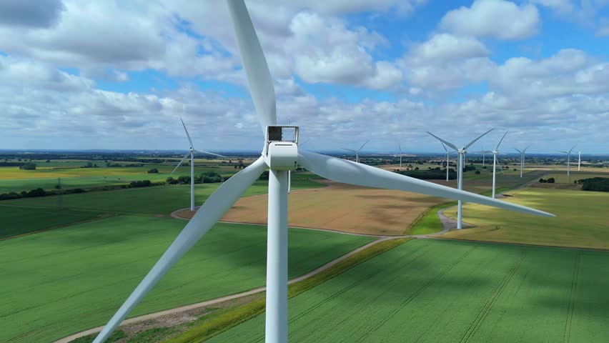 Aerial drone view of wind turbines in rural green golden landscape, renewable energy generation electricity, wind mill infrastructure, Lincolnshire England UK