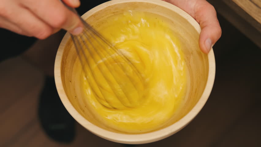 Whisking fresh and flavorful eggs in a beautifully crafted wooden bowl for a delightful breakfast