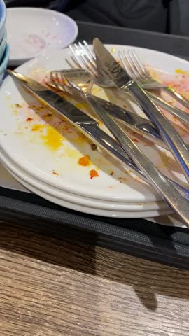 Dirty dishes stacked with utensils on a tray, creating a post-meal dining concept video