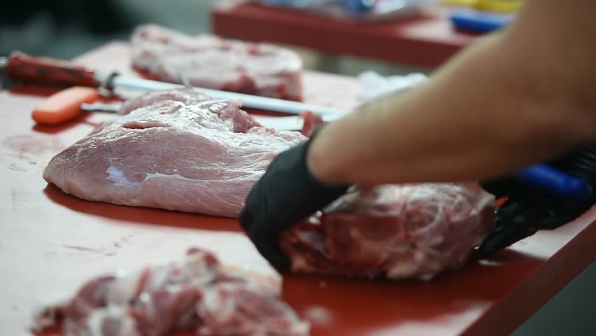 Butcher cutting pork primal meat cuts, such as the leg, loin, rack, and shoulder
