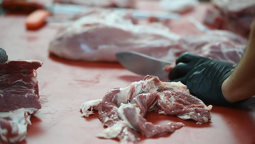 Butcher cutting pork primal meat cuts, such as the leg, loin, rack, and shoulder
