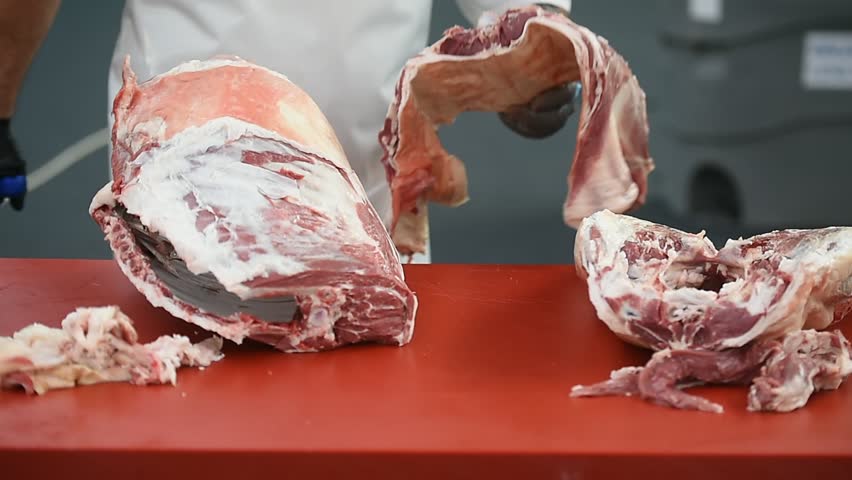 Butcher cutting pork primal meat cuts, such as the leg, loin, rack, and shoulder