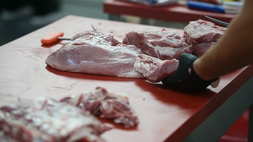 Butcher cutting pork primal meat cuts, such as the leg, loin, rack, and shoulder