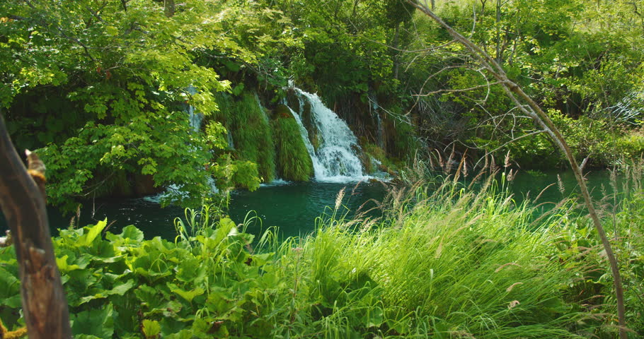 Small waterfall cascading over rocks surrounded by lush vegetation Plitvice Lakes National Park summer Croatia
