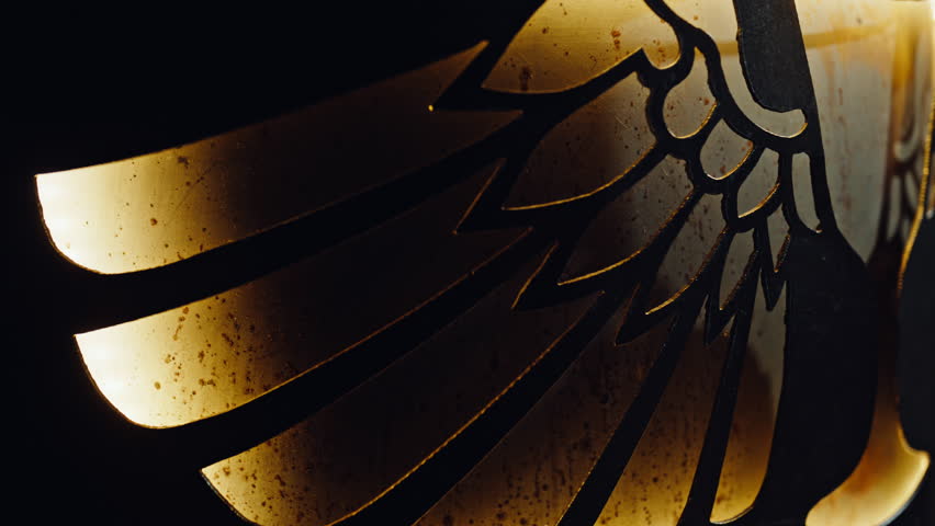 Metal wings engraved at artistic bar interior closeup. Carved feathers reflecting soft light expressing crafted detail in nightlife environment. Abstract sign revealing symbolic design on pub wall. 