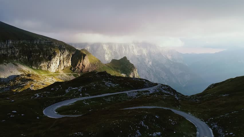 Cinematic drone of Mangart mountain pass glowing at sunset in Slovenian Alps