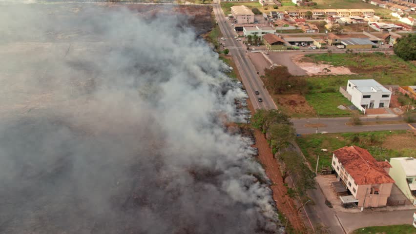 Aerial reveals thick smoke over dry vegetation and traffic corridors during a regional heatwave