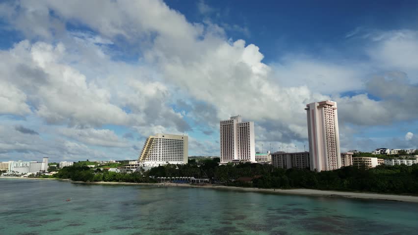 Stunning aerial orbit of tropical island resorts and coastal hotel buildings with cloudy background during daytime - Guam, USA