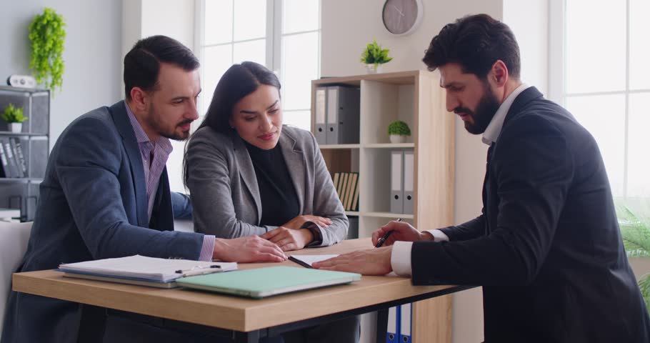 Realtor meeting with couple, looking through contract and other documents, considering variation, making presentation offer, meeting in office. Male financial advisor giving consultancy