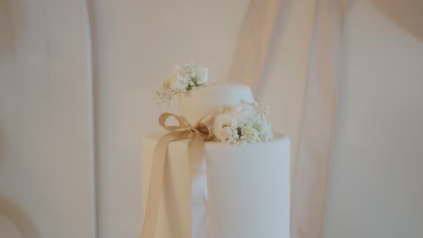 elegant two tier wedding cake adorned with white flowers and ribbon