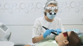 Dentist performs a dental procedure with a laser device on a child patient wearing protective glasses in modern clinic. Professional pediatric dental care and medical technology. - Powered by Shutterstock - Get 15% off with code: PIKWIZARD15