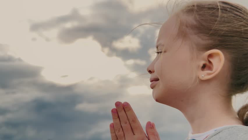 Innocent prayer on a cloudy day, Girl s spiritual connection, Faith in young hearts, Little hands folded in hope, Childhood innocence and belief, Kid looking up to the heavens, Peaceful prayer moment