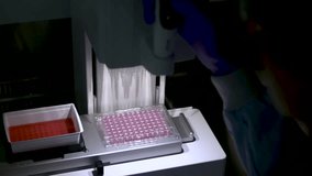 Detailed view of a woman scientist operating an automatic pipette machine, moving orange liquid between containers in a professional laboratory —themes of science, precision, technology, and research. - Powered by Shutterstock - Get 15% off with code: PIKWIZARD15