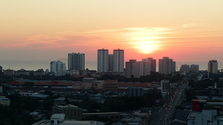 Orange and yellow sunset over a coastal city with tall buildings and traffic