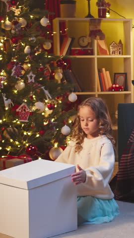 Kid under Christmas tree and openinig a Christmas present. Christmas gifts. Gifts under the New Year tree and child opens a gift Celebrating Christmas and New Year.