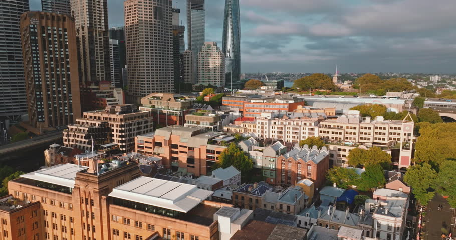 Australia, Sydney City: modern downtown skyscrapers and historic low-rises buildings houses under bright cloudy sky, highlighting urban development. Drone flight footage aerial view