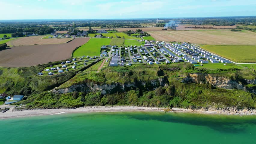 Aerial view of Omaha Beach in Normandy, France, with Flower Camping Omaha Beach nearby, historic WWII D-Day landing site, sandy coastline, green fields, and holiday atmosphere