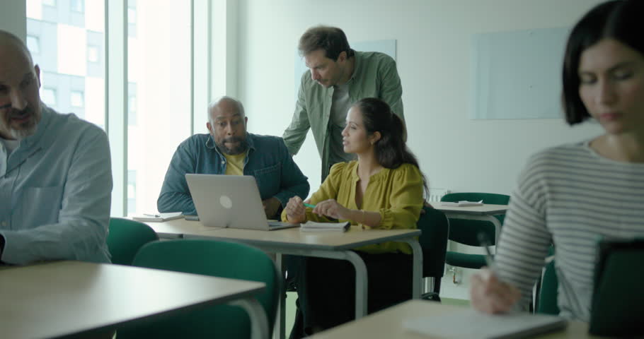 Teacher in Classroom Engaged with Adult Students Learning Technology