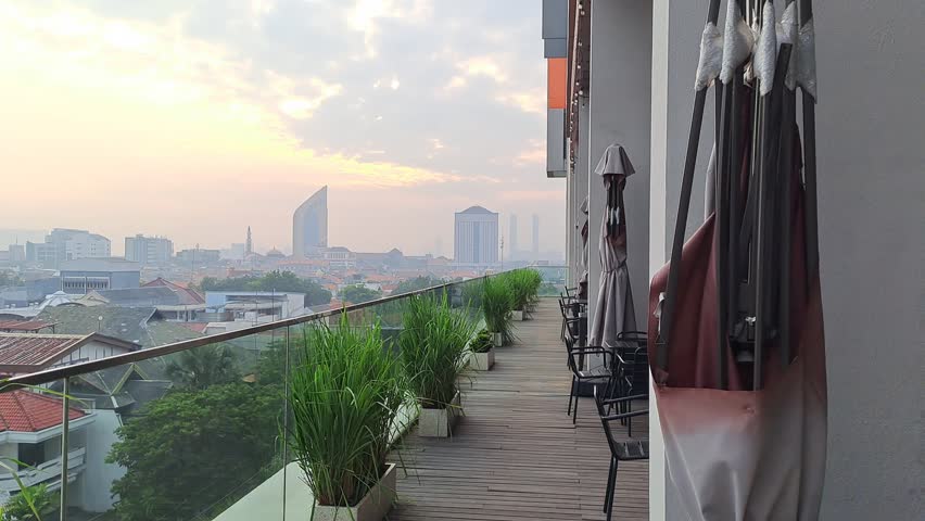 SURABAYA, INDONESIA - SEPTEMBER 18, 2025: Morning rooftop view of a big city with tall buildings and skyscrapers under a slightly cloudy sky, showcasing an urban metropolitan atmosphere.