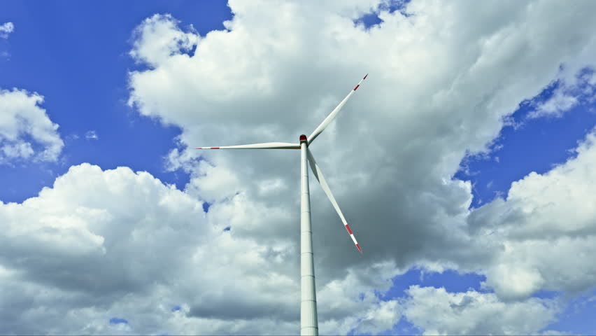 A powerful windmill generates energy against a blue sky. A wind turbine spins against a sky. Energy generation by wind turbines.