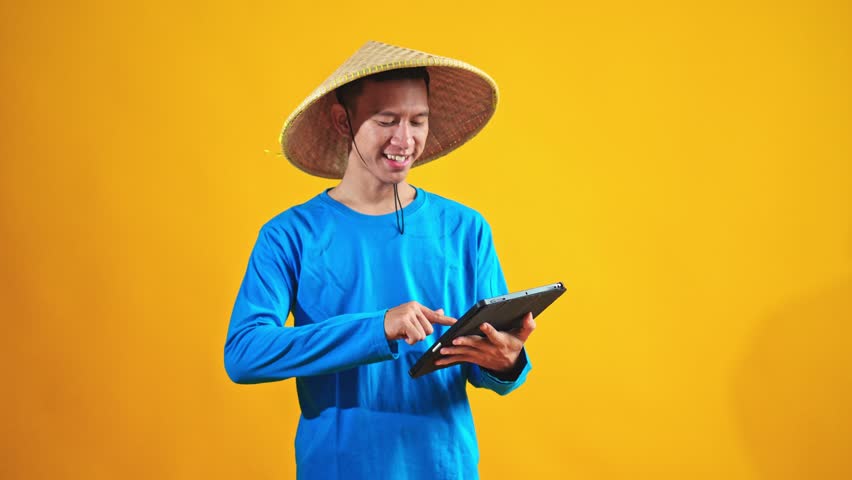 Young farmer skillfully uses tablet device for modern agricultural management and data analysis