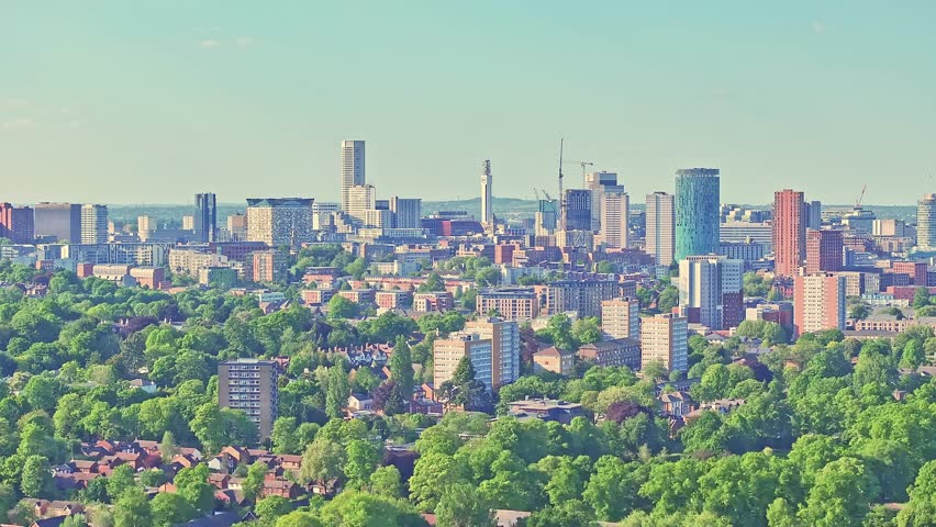Birmingham skyline towering over verdant Cannon Hill Park, blending modern architectural silhouettes with lush green landscape, drone slow ascend