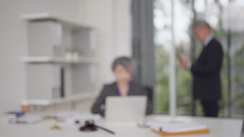 Blury professional environment shows adult legal experts managing cases. Office tools symbolize law justice integrity diligent work ethic.