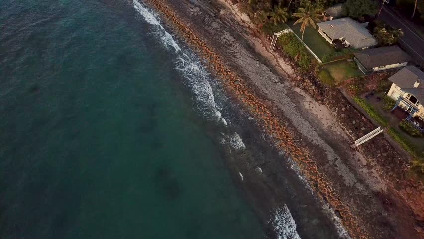 Luxury waterfront villas with palm tree and beach access at sunset. Aerial top down shot. Kawela, Hawaii. Quiet atmosphere.