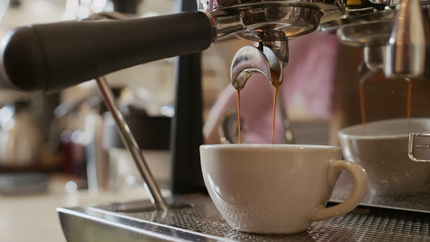 Close up shot of professional coffee machine pouring coffee into cup at cafe counter