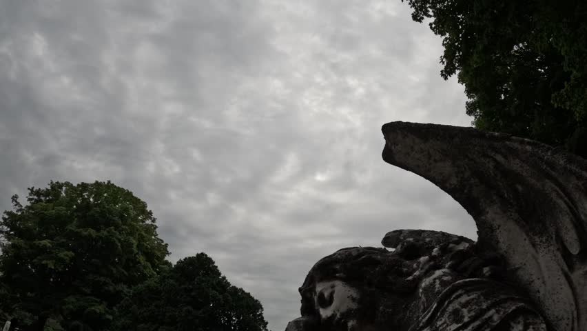 A stone angel sleeps as rain clouds speed overhead.