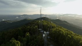 Aerial orbit of radio cell tower on top of green mountains at sunrise. Wide shot. Green valley and forest landscape in USA. Autumn season in America. Connecting houses and homes with wireless signal. - Powered by Shutterstock - Get 15% off with code: PIKWIZARD15