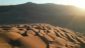 Sweeping drone footage over vast rippled dunes, with long shadows stretching across the barren desert landscape. - Powered by Shutterstock - Get 15% off with code: PIKWIZARD15