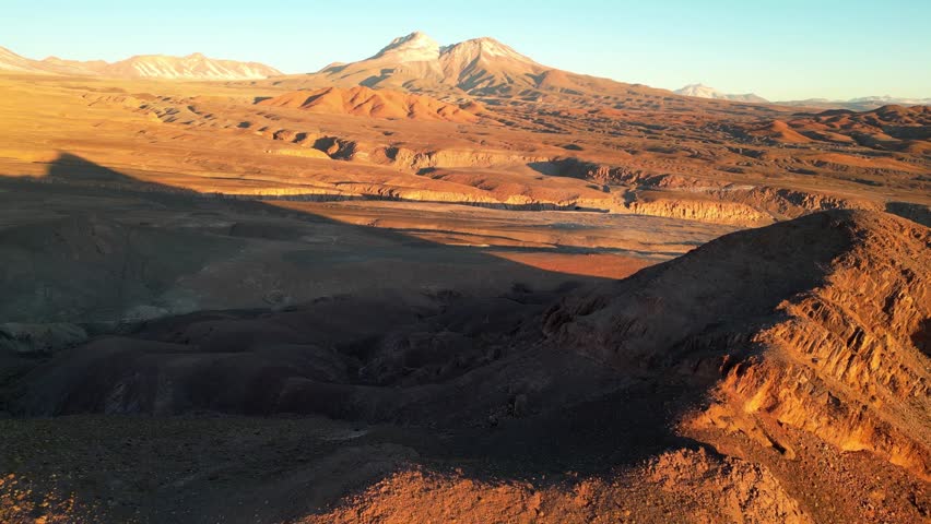 Drone footage flying over Chile’s Valle de la Luna, with rugged desert terrain glowing in soft twilight colors.