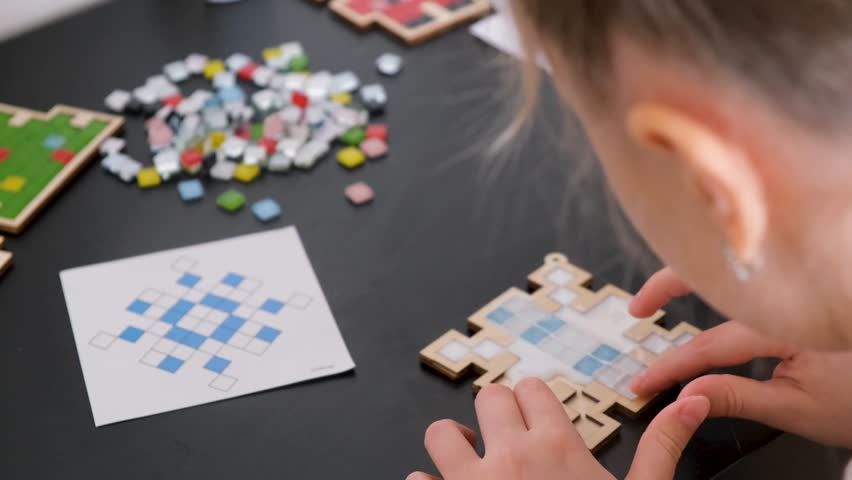A girl makes a Christmas toy with her own hands from ceramic mosaic. Ceramic mosaic, DIY Christmas tree toy. Eco-friendly toy, educational activity for children.