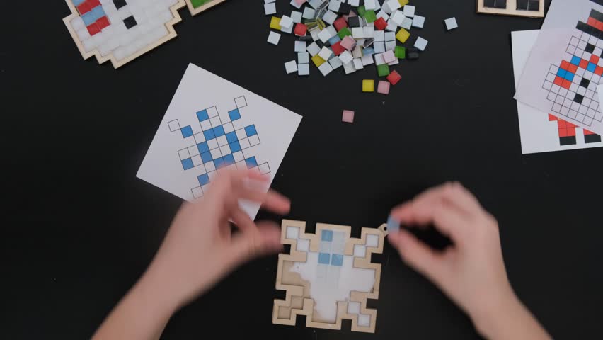 A girl makes a Christmas toy with her own hands from ceramic mosaic. Ceramic mosaic, DIY Christmas tree toy. Eco-friendly toy, educational activity for children.