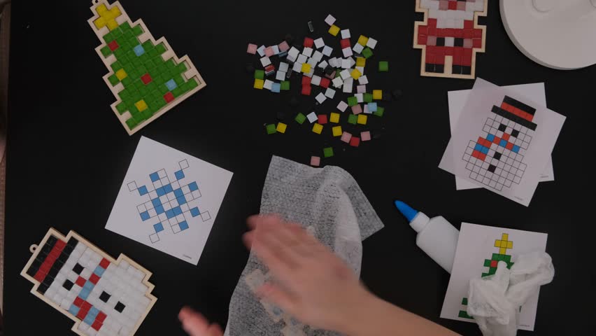 A girl makes a Christmas toy with her own hands from ceramic mosaic. Ceramic mosaic, DIY Christmas tree toy. Eco-friendly toy, educational activity for children.