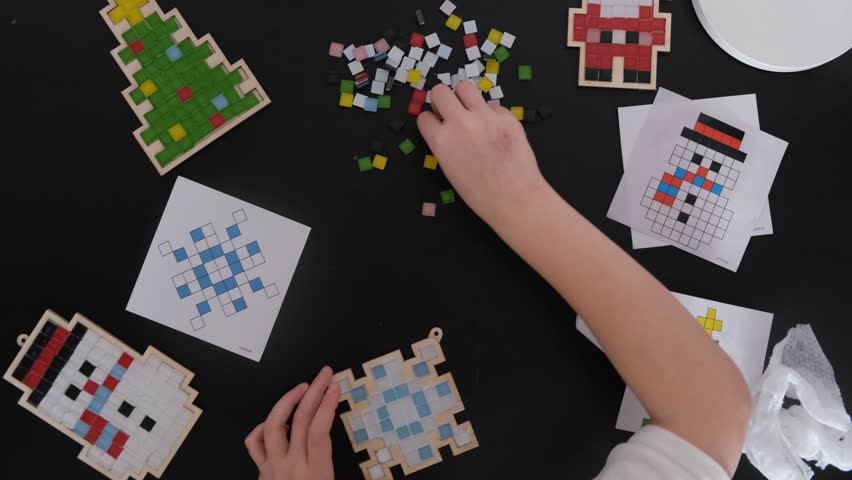 A girl makes a Christmas toy with her own hands from ceramic mosaic. Ceramic mosaic, DIY Christmas tree toy. Eco-friendly toy, educational activity for children.
