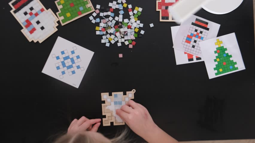 A girl makes a Christmas toy with her own hands from ceramic mosaic. Ceramic mosaic, DIY Christmas tree toy. Eco-friendly toy, educational activity for children.