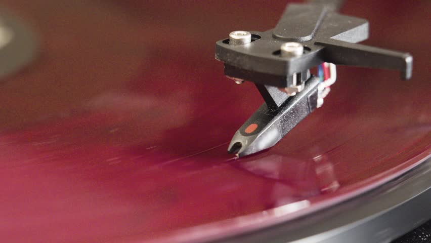 Turntable disk vinyl record player close-up 4K footage. Close-up 4K shot of a red vinyl record spinning on a classic turntable player.