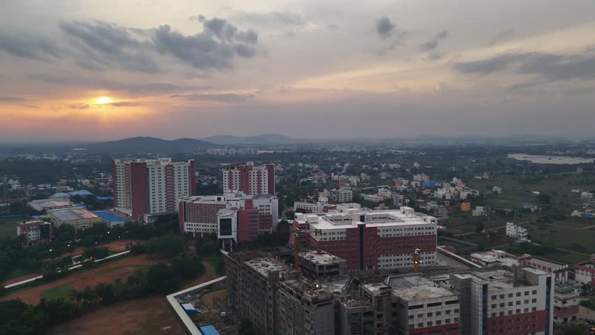 Aerial view of urban development near a large lake. Footage shows modern residential buildings, some finished and some under construction, highlighting the growth of a new city district. VIT Chennai