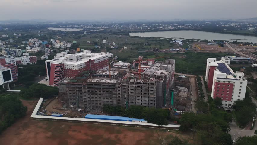 Drone footage captures a developing city with new high-rise apartments and active construction sites situated beside a calm lake. Perfect for projects on real estate and city expansion. VIT Chennai
