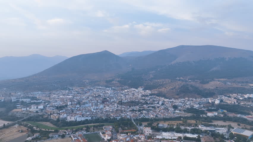 Day break aerial across the historic township of Loja and the Genil river on a hazy Autumn day, towards the imposing Sierra de Loja mountains. Granada Spain Espana