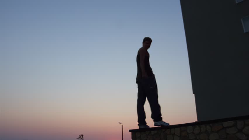 Silhouette of a guy doing an acrobatic backflip against a sunset sky