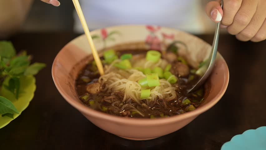 Young Asian woman eating famous Thai street food boat noodles served at restaurant in Thailand