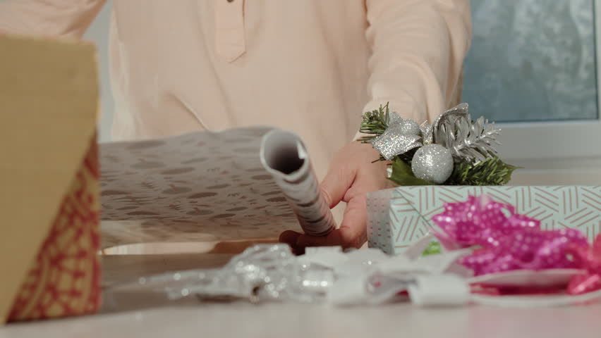 Unrolling wrapping paper near decorated gift box