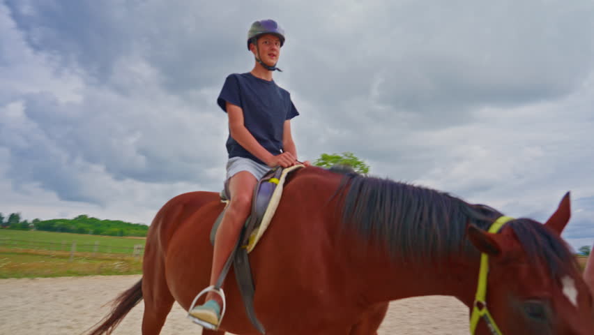 Happy teenager boy sitting on horseback practicing horse riding