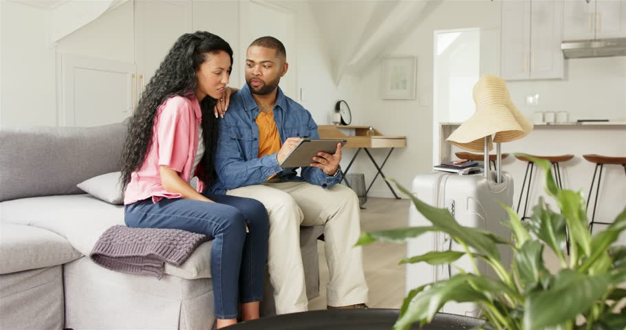 Entering living room African American couple opening tablet, tapping items, entering card details. Technology, lifestyle, modern, intimacy, collaboration, leisure, cozy